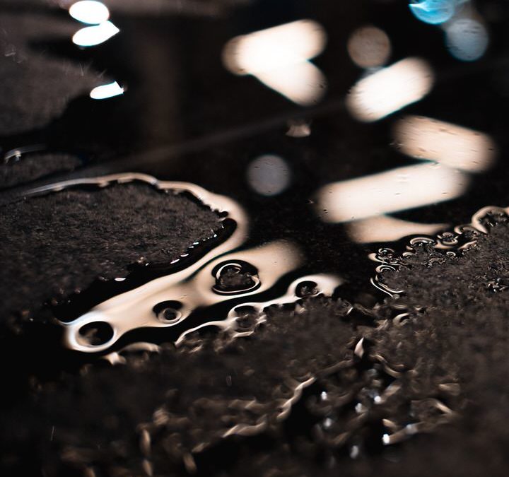 An extreme close-up shows a puddle of spilled coffee on a black surface.